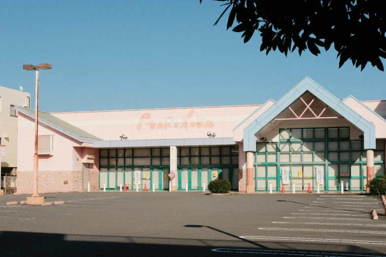 the front of a pink and green building with lots of doors