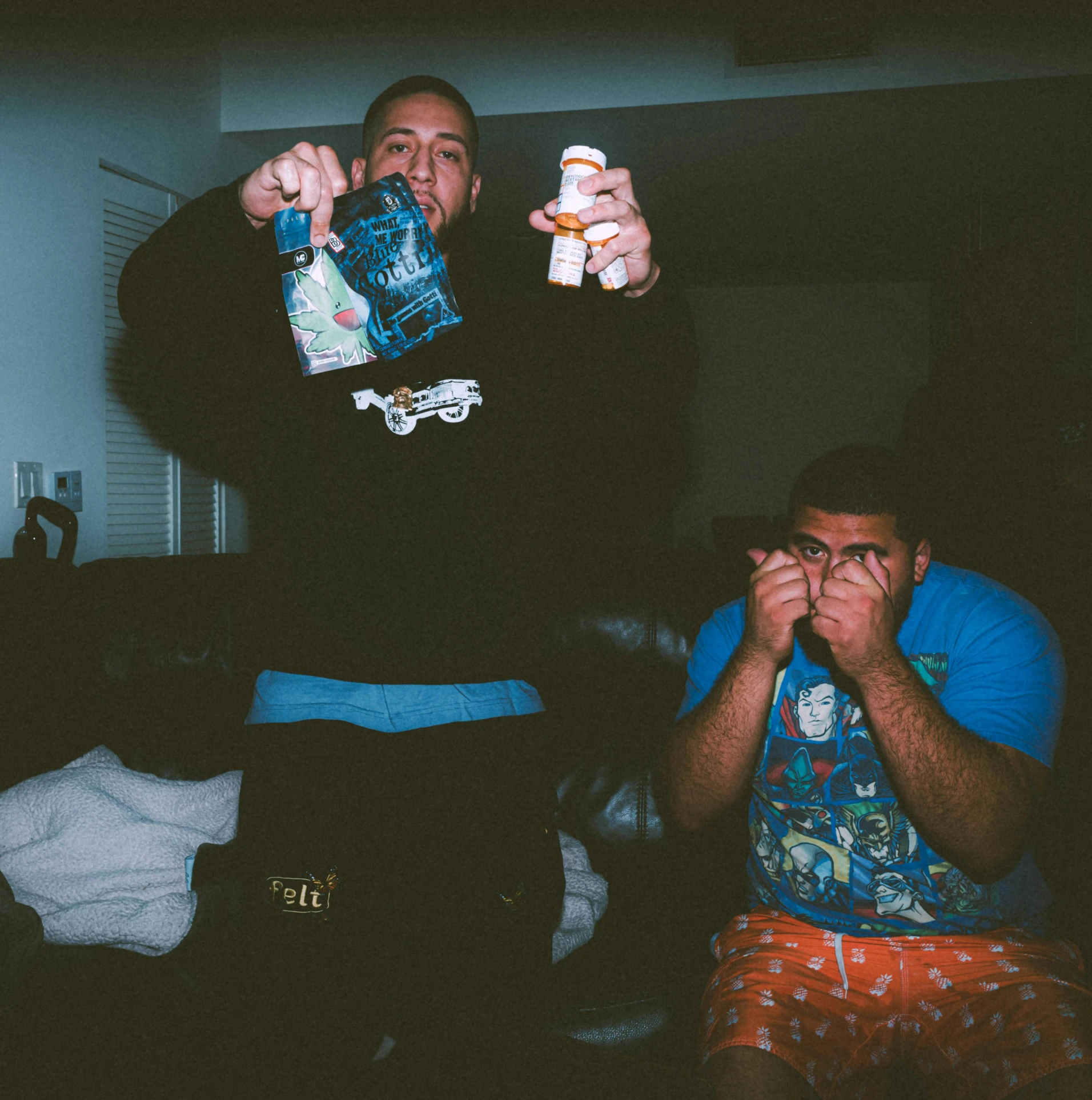 two men standing in a dark room holding a remote