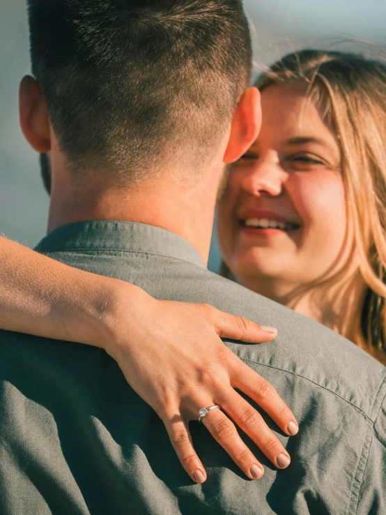 a man and woman who are hugging while the man is wearing a ring on their hand