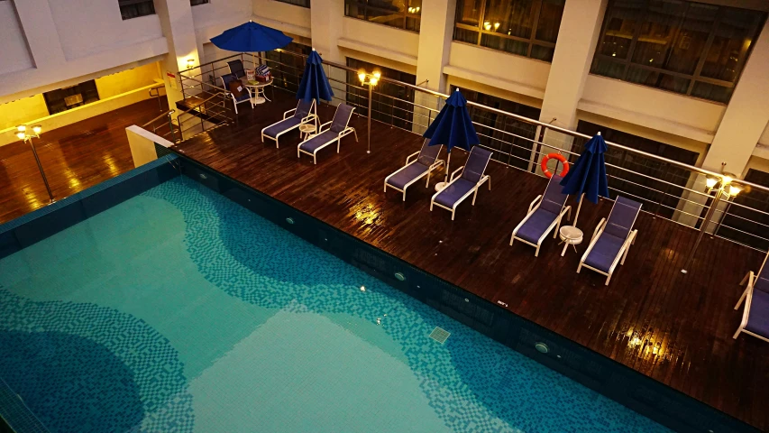 the view from the room's roof shows the pool, sun lounges and tables with blue umbrellas