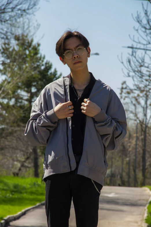 a young person wearing glasses and a grey jacket