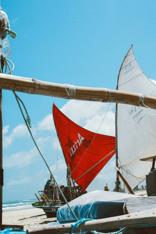 sail boats sitting on the sand at a beach