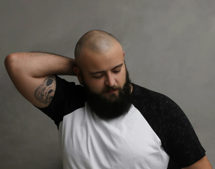 a bald man in a black and white shirt covers his head