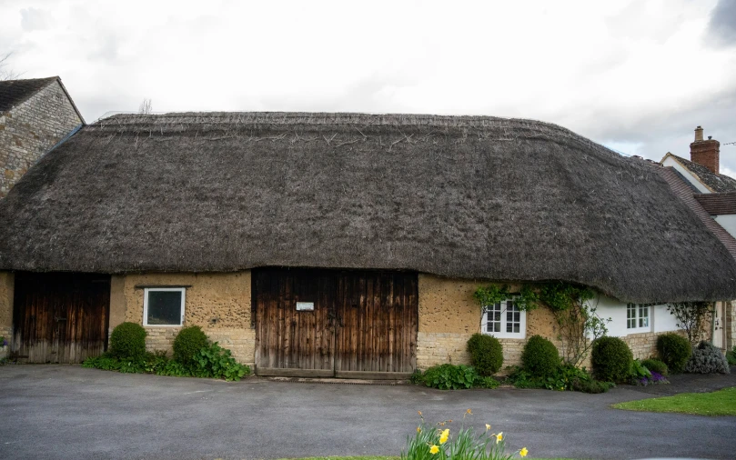 an old thatched roof house with a garage