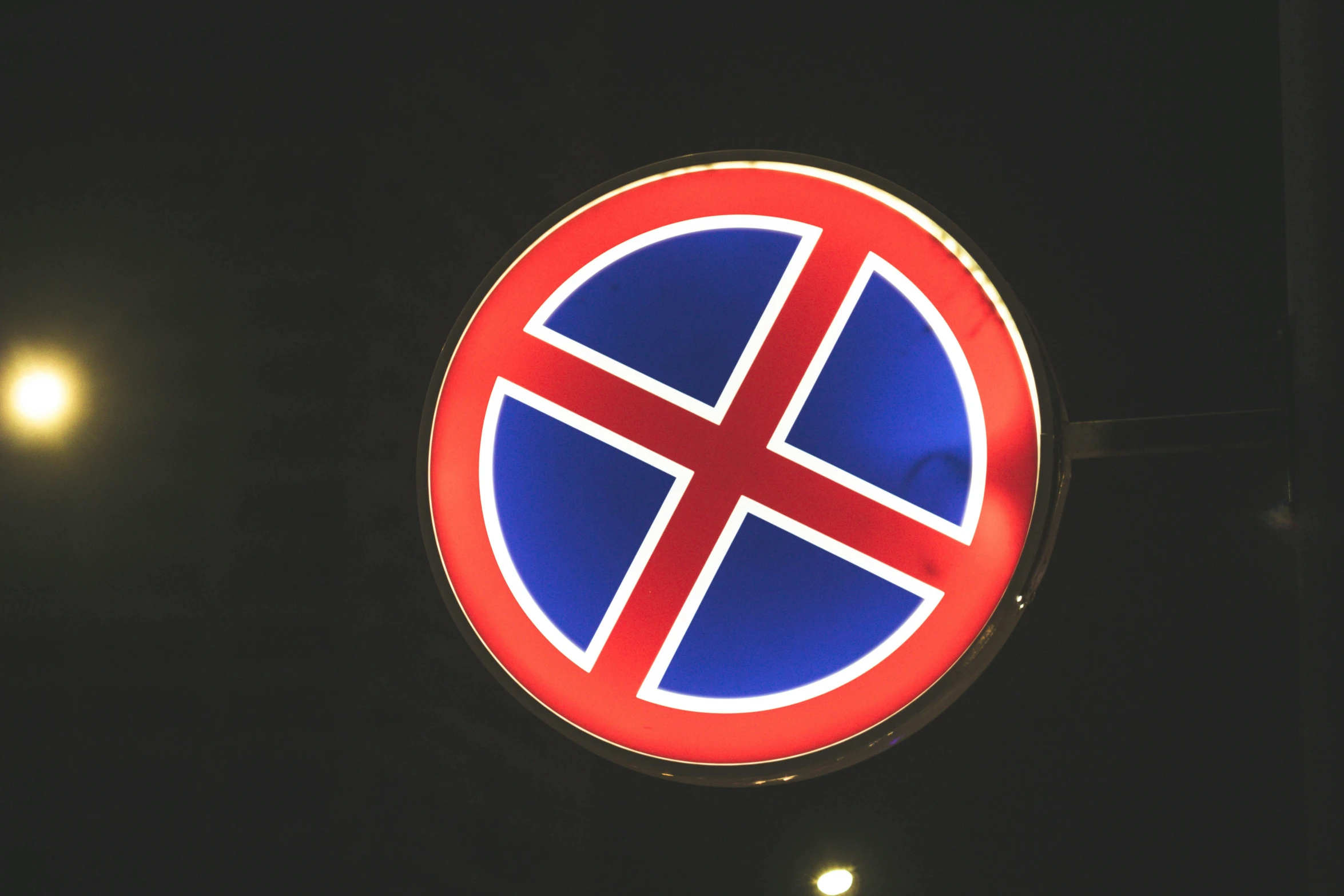 a red and blue circle shaped sign hanging from the side of a building