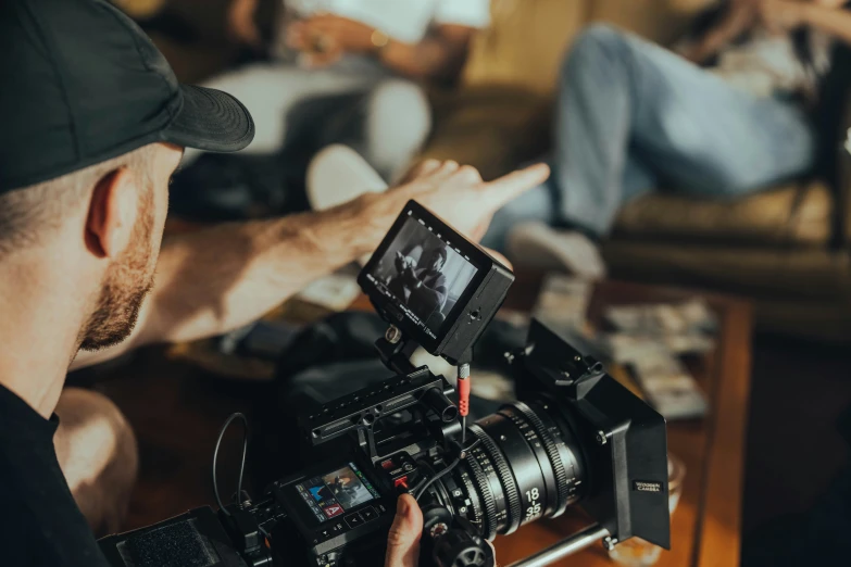 a man in cap is using a camera on a table