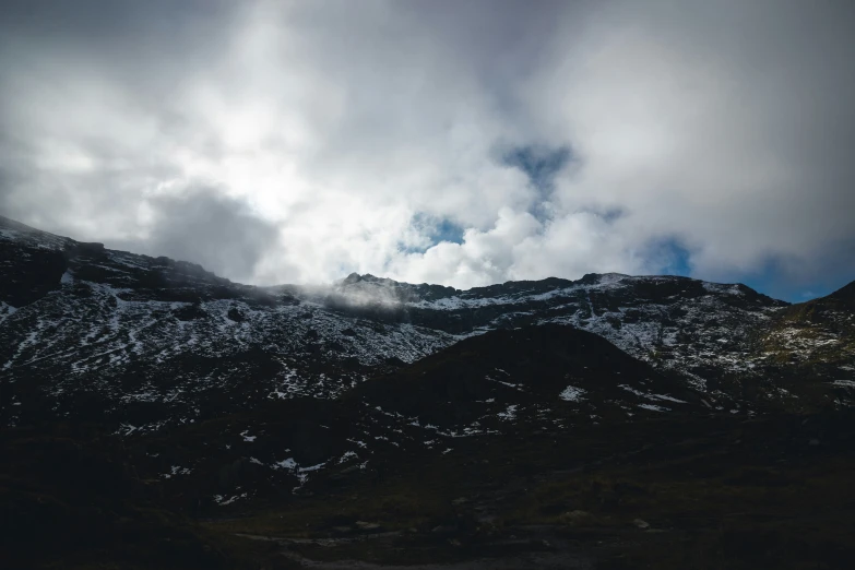 there is a snow covered mountain with clouds over it