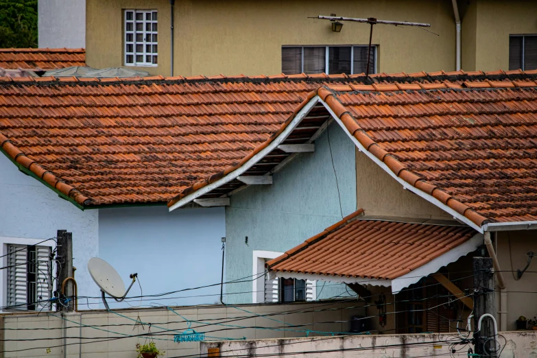 many brown tile roofs on three buildings, one is tan