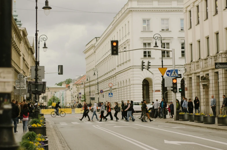 a crowd of people crossing the street in front of a large building