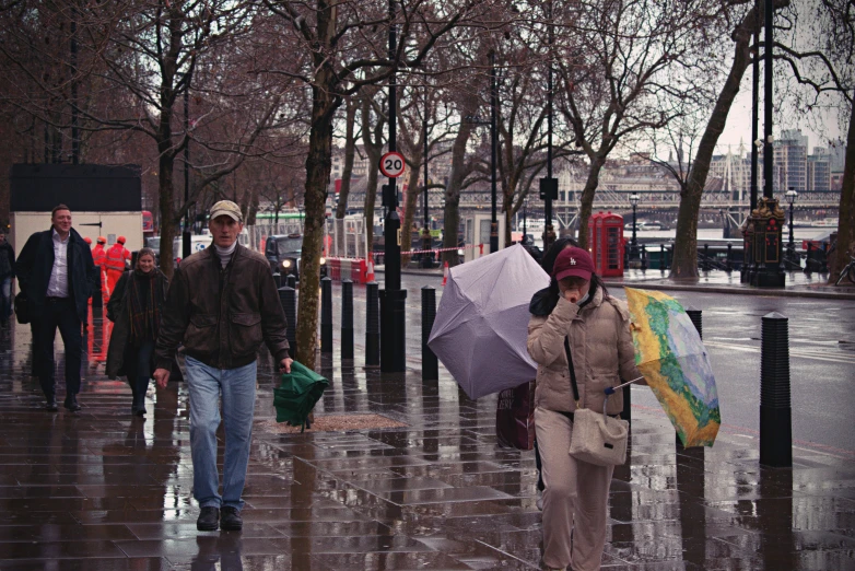 several people are walking on a city street while holding umbrellas