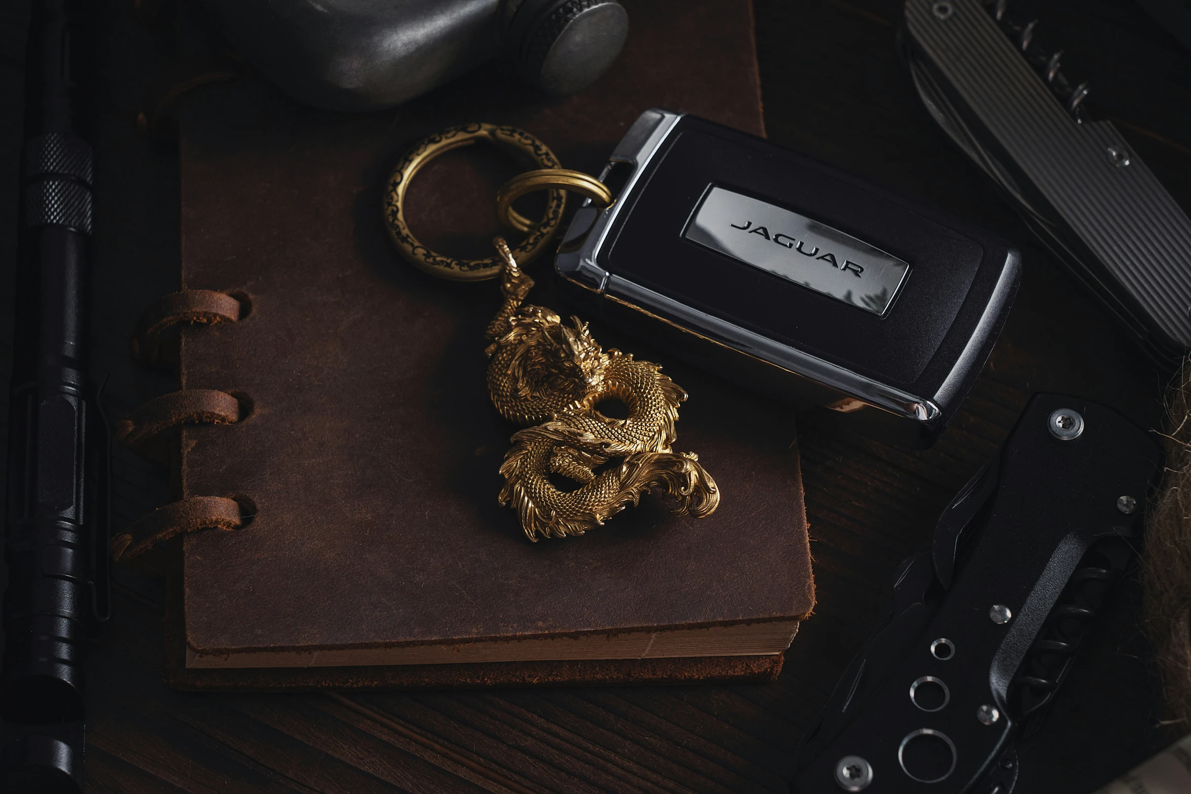 a black and gold keychain is next to a brown book