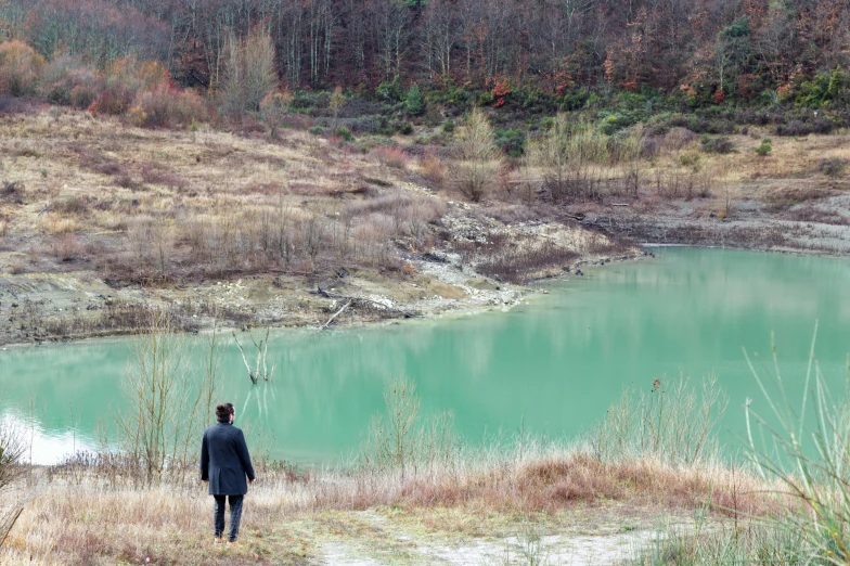 the man is standing alone near the large water lake