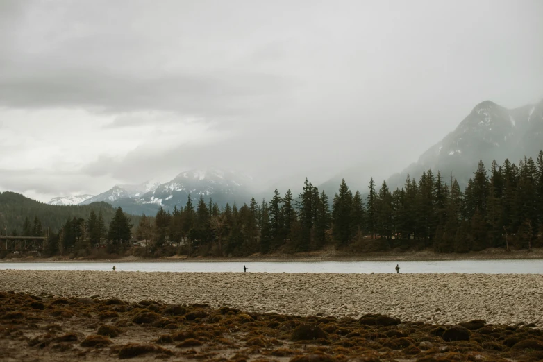 a man and two people are riding their horses along the water