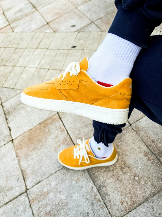 feet in yellow sneakers, white socks and black pants