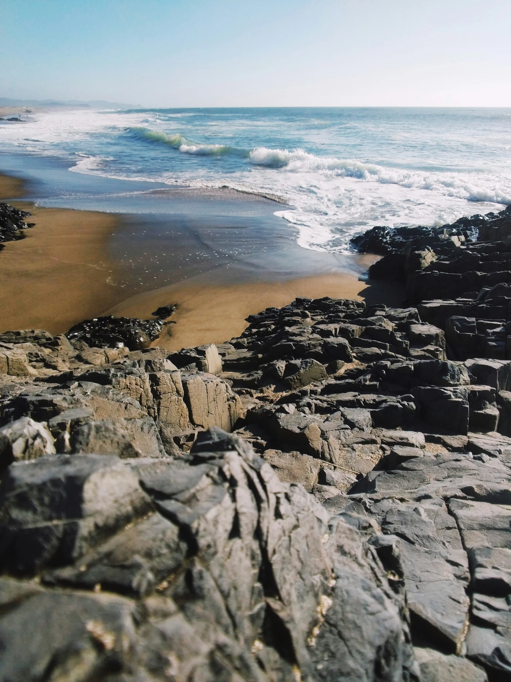 a rocky beach and a wave crashing into the water