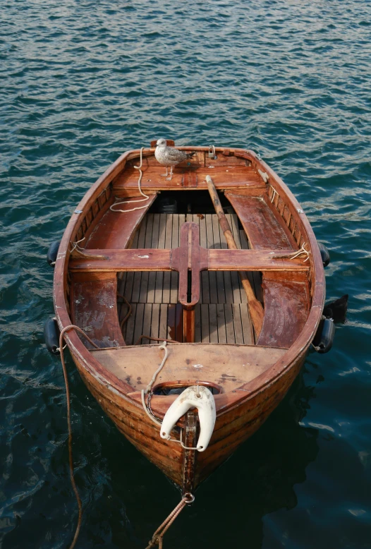 a boat with a wooden deck is tied up to the water