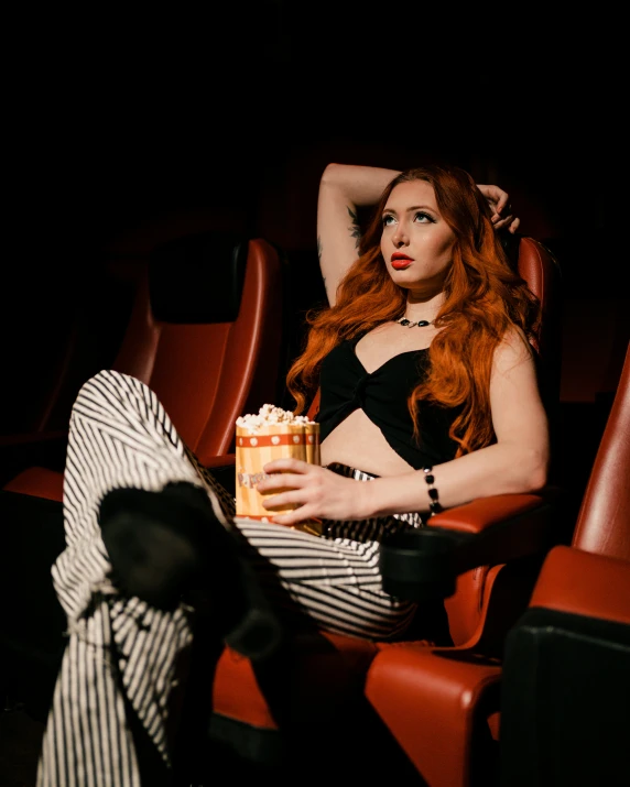 a beautiful woman in black sitting down and holding a cup