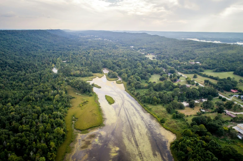 an aerial view of a small stream near the green countryside