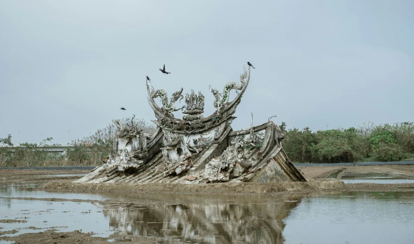 a piece of driftwood in water with birds flying over it