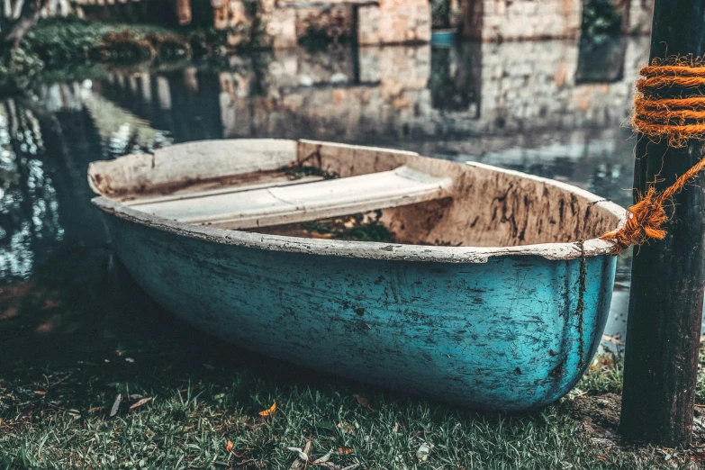 an old wooden row boat on the edge of a body of water