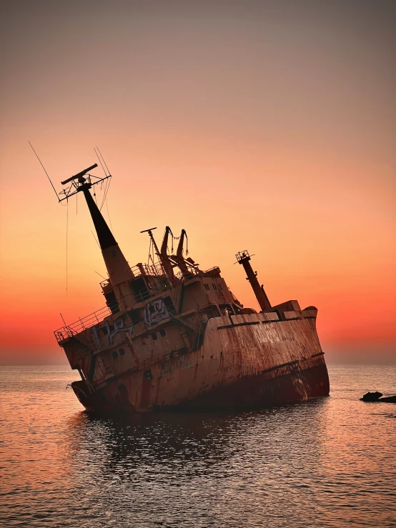 the ship is sinking in water at sunset