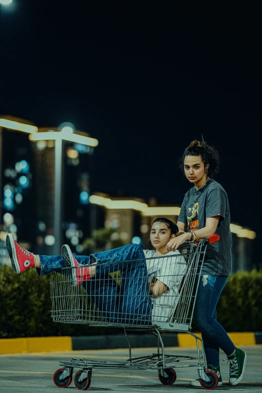 two people hing a shopping cart with the person lying on it