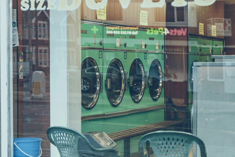 the outside of a laundry shop showing a row of large green washing machines