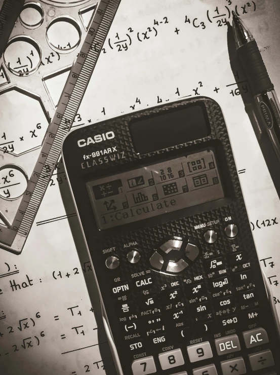 a calculator and pen sitting on top of some papers