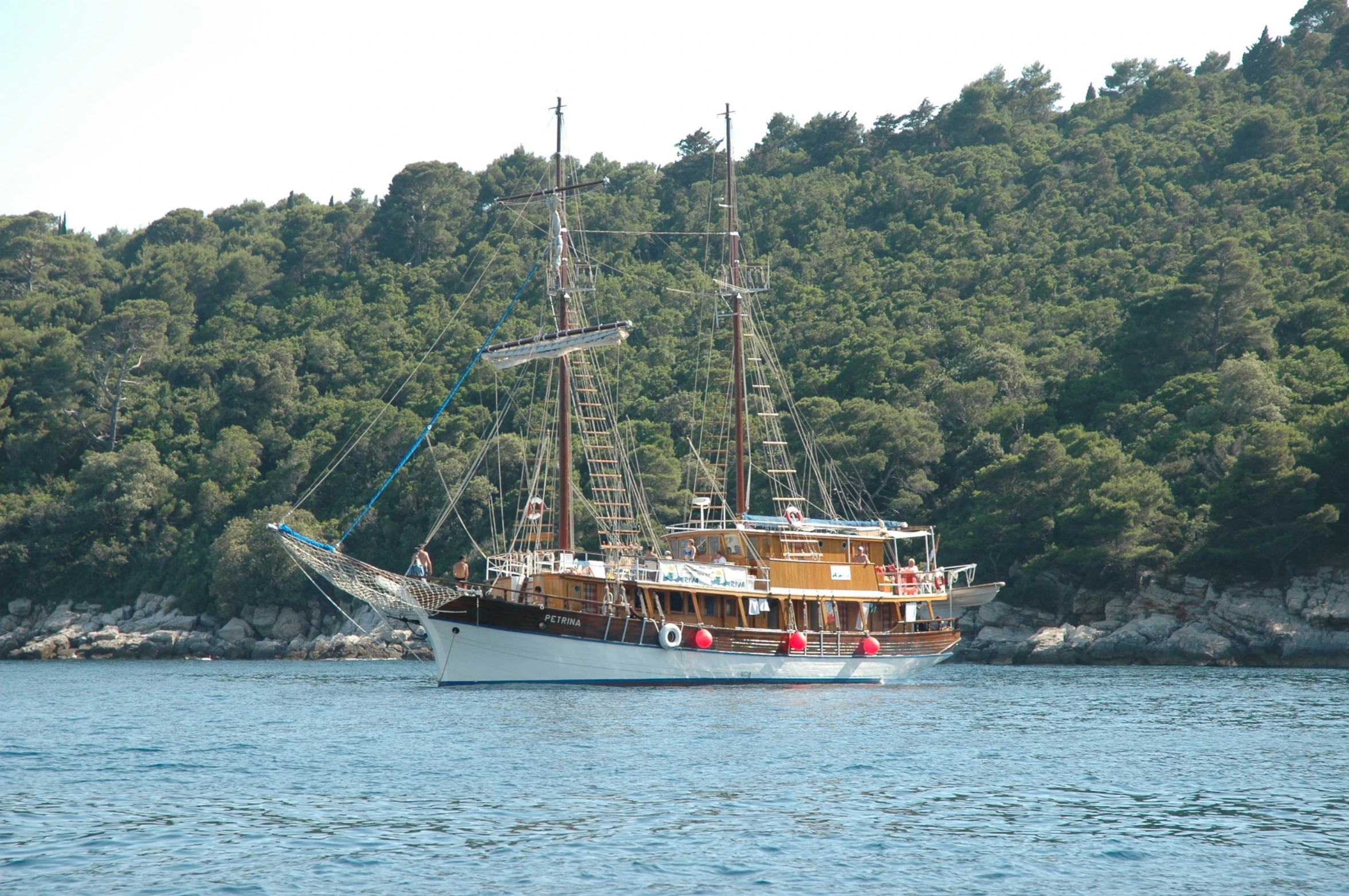 a boat sailing in front of a large green mountain