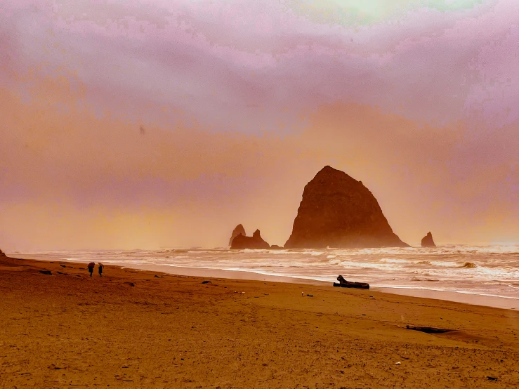 a large rock in the distance on the beach