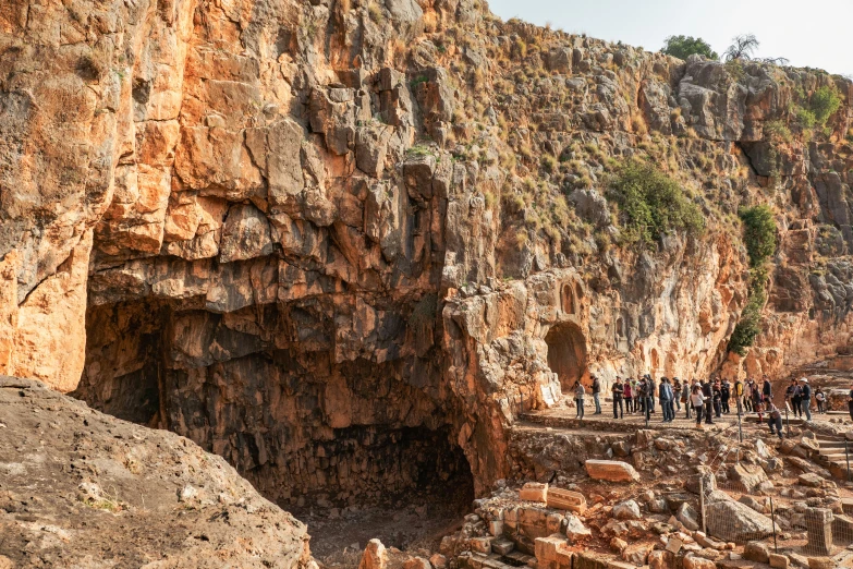 a group of people standing at the bottom of some cliff faces