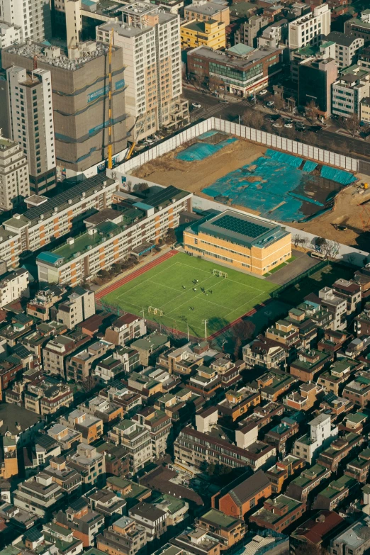 an aerial view of a large field next to buildings