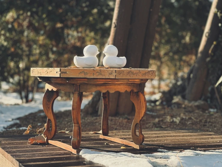 there is a small table with two white ducks sitting on top