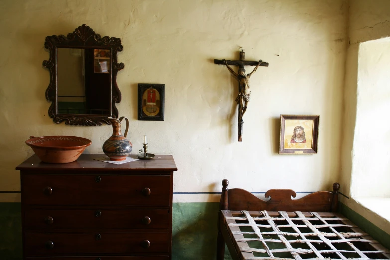 an old room with a crucifix and wooden dresser