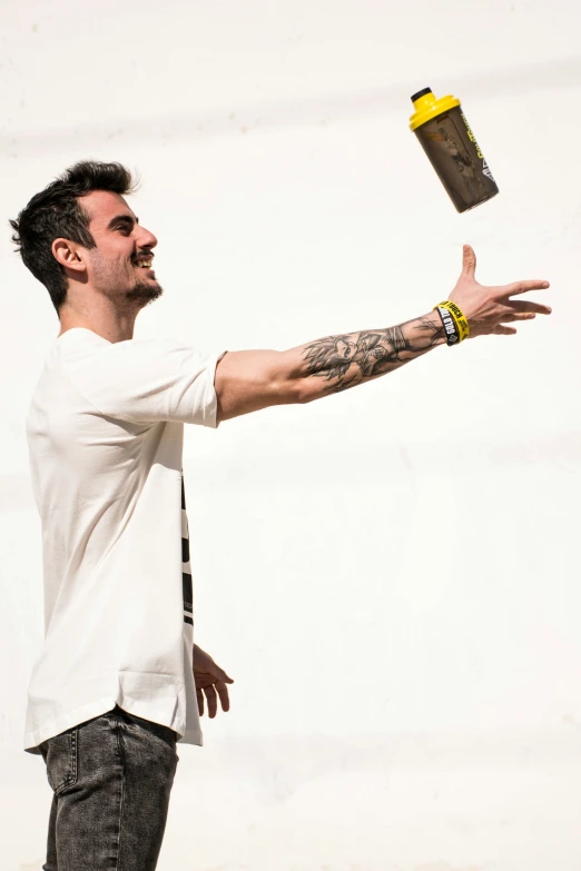 a man with a white shirt and tattoos holding out his hand