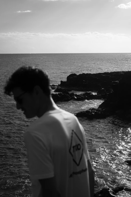 a man standing on a rock outcropping looks at the ocean