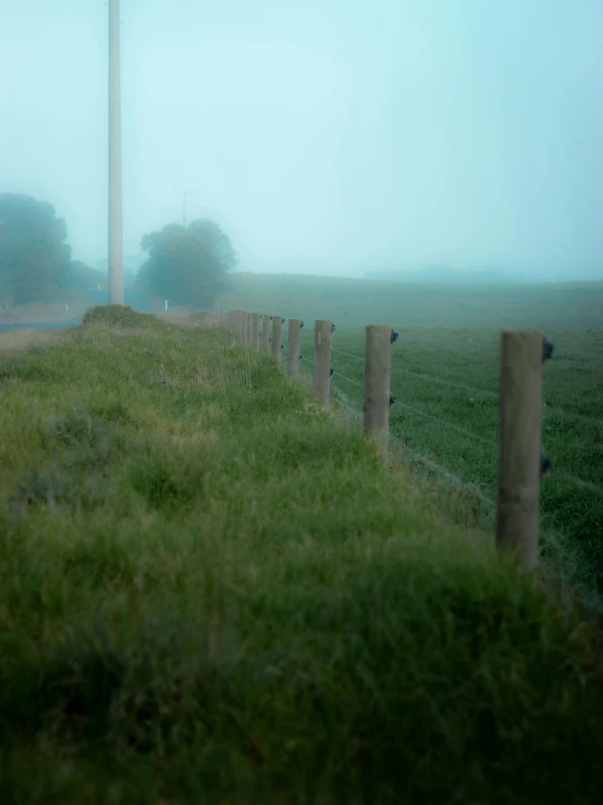 a stop sign in a foggy field next to a fence