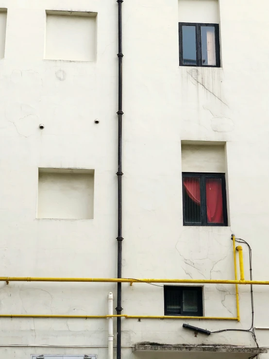 a long yellow pole with window frames on the side of a building