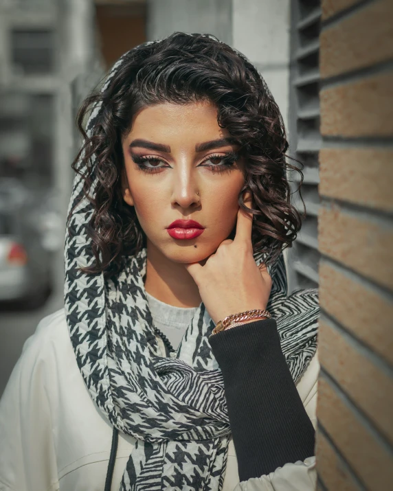a young woman with dark curly hair and dark eyeliners, wearing a scarf