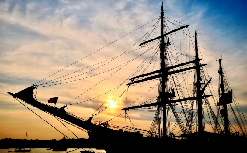 a ship sailing through a harbor at sunset