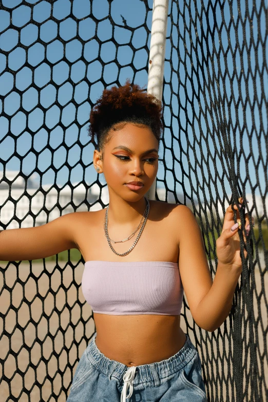 the girl poses near a chain link fence