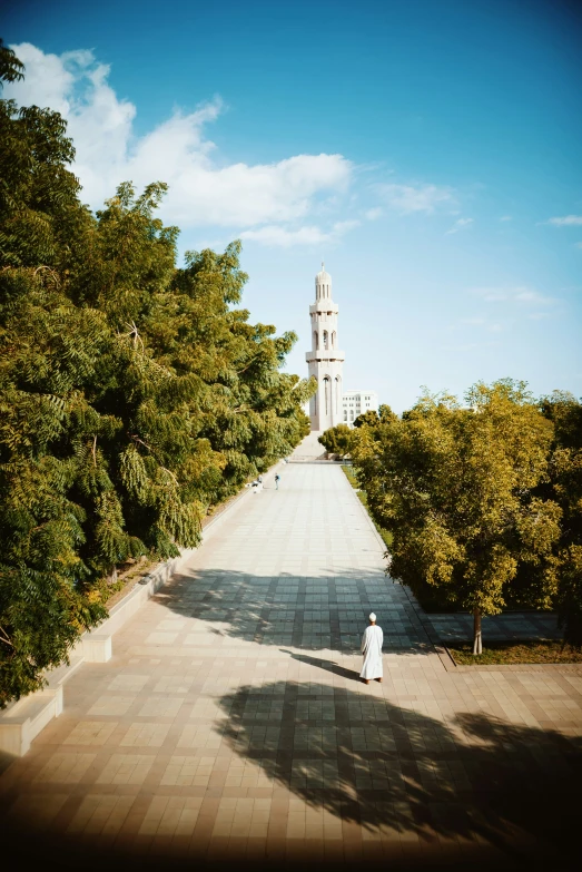 a man is walking down a large path with trees