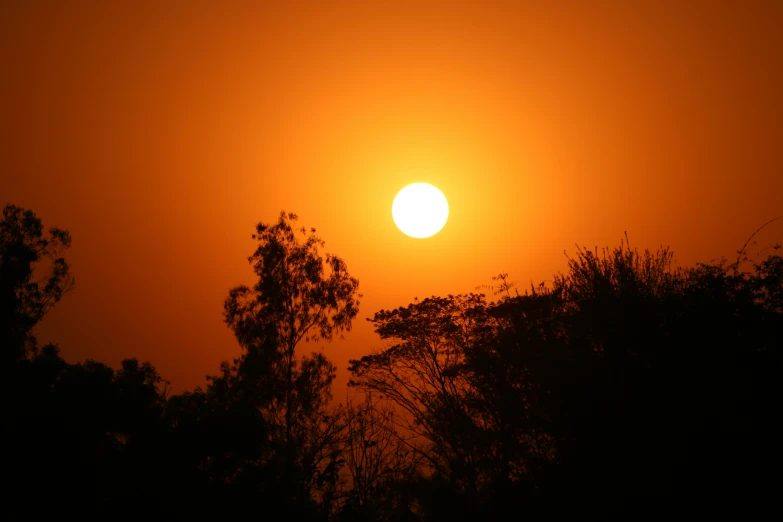 a sunrise with a large cloud and the sun setting in a dark sky