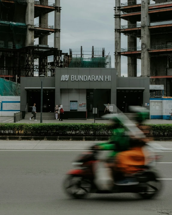 the motorcyclist is riding past an unfinished building