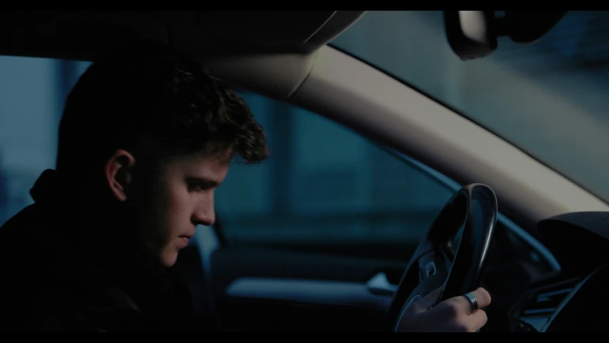 a man sitting in a car while holding his hands up