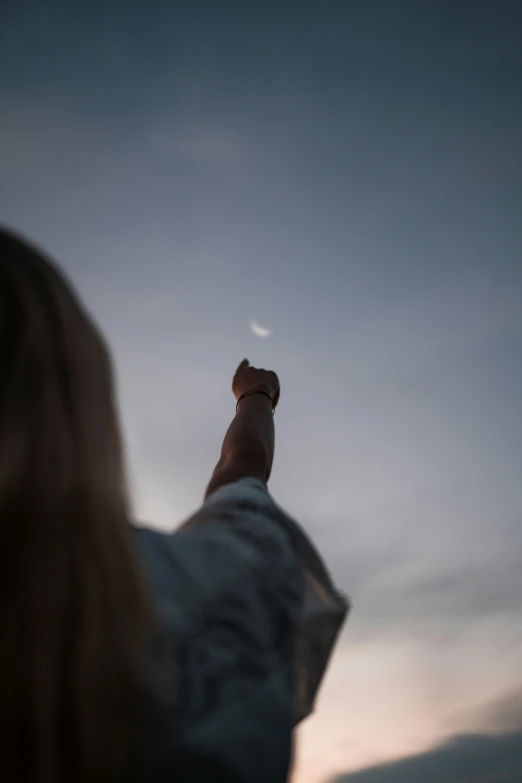 a young lady holding up her hand at the sky