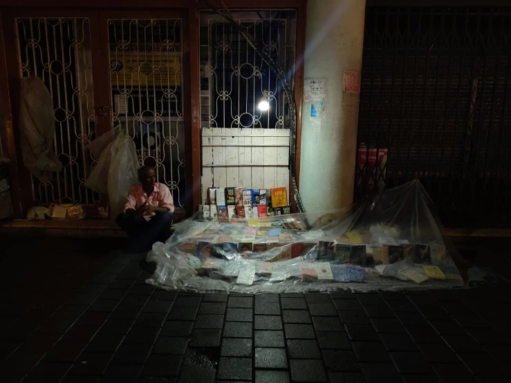 an elderly man sitting outside a store at night