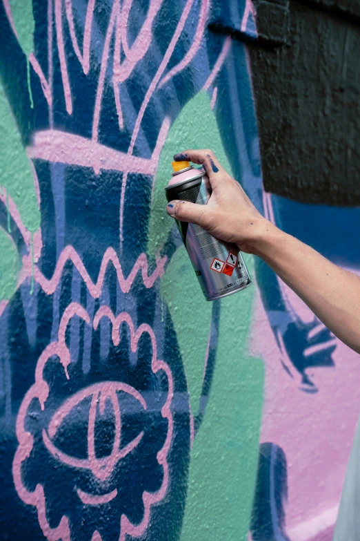 someone's hand holding a spray bottle on a wall