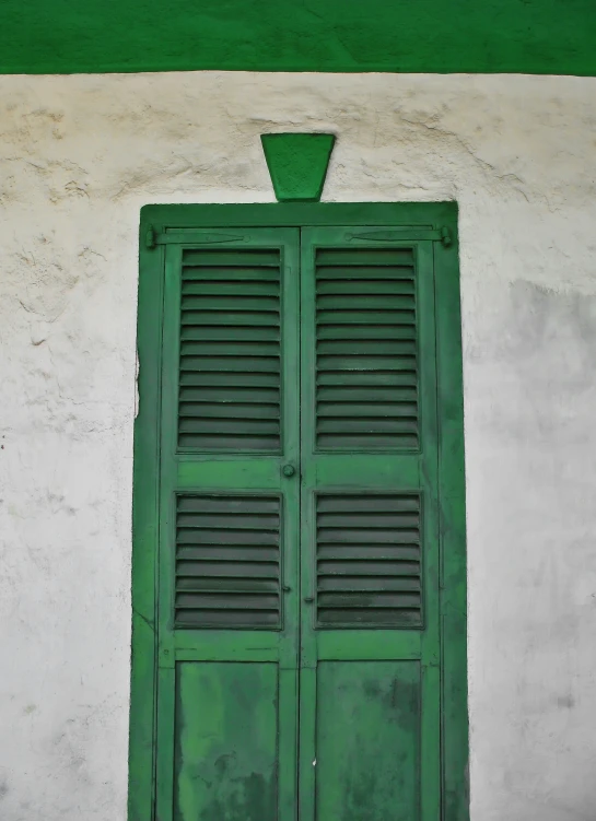 a close up of a green window with a white wall