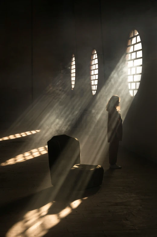 a woman standing alone next to luggage in the dark